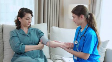 Bakıcı Kafkasyalı genç hemşire hastanın tansiyonunu ölçüyor nabız ölçümü ve evdeki oturma odasında muayene, sağlık, sağlık ve sigorta kontrolü.