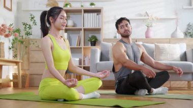 Genç Asyalı çift evdeki oturma odasında yoga ve meditasyon yapıyor. Rahatlama, sağIık ve sağlıklı yaşam için kadınla yoga hocası, yoga ve sağlık sporu yapıyor..