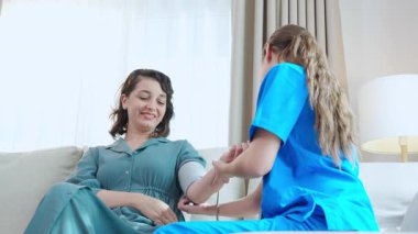 Bakıcı Kafkasyalı genç hemşire hastanın tansiyonunu ölçüyor nabız ölçümü ve evdeki oturma odasında muayene, sağlık, sağlık ve sigorta kontrolü.