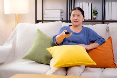 Asyalı bir kadın evdeki oturma odasında uzaktan kumandayla televizyon seyrediyor, mutlu bir kadın rahat rahat film izleyip eğleniyor, keyif alıyor ve yaşam tarzını tatmin ediyor..