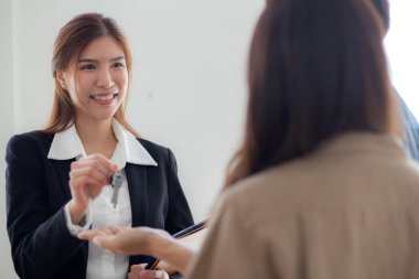 Mutlu Asyalı çift ev satın aldıktan sonra emlakçıdan ev anahtarı alıyor, ev sahipliği ve ipotek kredisi, yatırım ve ipotek, emlakçıya danışan çift..