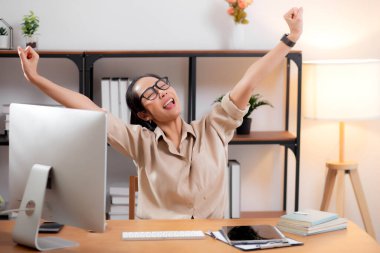 Genç Asyalı iş kadını, modern ev ofisinde başarılı olmak için masaüstü bilgisayarını kullanıyor. Masaüstü bilgisayarıyla çalışan bir iş kadını, evde oturma odasında kazanırken ve tatmin olurken, iş konseptini kullanıyor..