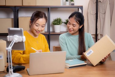 Çevrimiçi iş planlarken çalışan iki genç Asyalı kadın ve evde tablet ile sipariş kontrolü, çevrimiçi satıcı ile perakende satış, girişim işi ve kargo, nakliye ve hizmet.