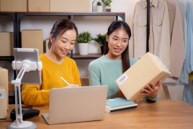 Çevrimiçi iş planlarken çalışan iki genç Asyalı kadın ve evde tablet ile sipariş kontrolü, çevrimiçi satıcı ile perakende satış, girişim işi ve kargo, nakliye ve hizmet.