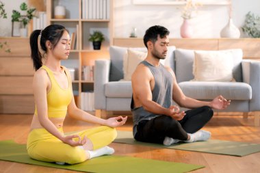 Genç Asyalı çift evdeki oturma odasında yoga ve meditasyon yapıyor, rahatlama, sağIık ve sağlıklı yaşam tarzı, yoga ve sağIık için spor yaparak sakin ve dingin bir yaşam sürüyor..