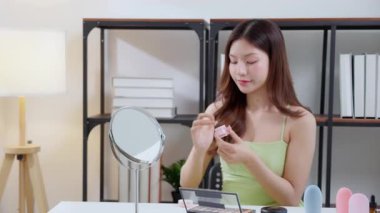 Güzel, genç Asyalı bir kadın evde aynaya bakarken kırışıklıklar için yüzüne krem sürüyor, güzel bir kadın yanağına losyon nemlendirici sürüyor, cilt bakımı ve güzellik, rahat bir şekilde kendine bakım yapıyor..