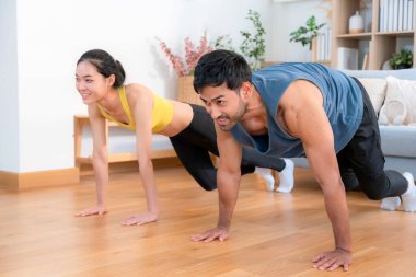 Mutlu genç Asyalı çiftler evlerinde birlikte dağcı egzersizleri yapıyor, gülümsüyor ve enerjik fitness eğitimi ve kardiyo rutini, sağlık ve refah motivasyonu..