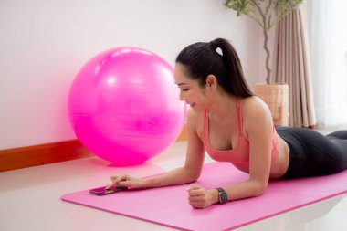 Genç Asyalı kadın, motivasyon ve azimle evde kalas üzerinde durarak antrenman yapıyor, kadın ağırlık antrenmanı yapıyor güçlü ve güçlü, tek bir kişi, yaşam tarzı ve spor konsepti..