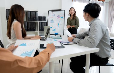 Grup Asyalı iş adamları raporlama ve sunum grafikleri ve grafikleriyle finansman hakkında ofiste toplanırken, meslektaşlar rapor ve stratejiyi, takım çalışması planlama ve analizi tartışacaklar..