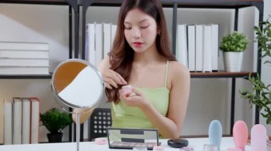 Güzel, genç Asyalı bir kadın evde aynaya bakarken kırışıklıklar için yüzüne krem sürüyor, güzel bir kadın yanağına losyon nemlendirici sürüyor, cilt bakımı ve güzellik, rahat bir şekilde kendine bakım yapıyor..
