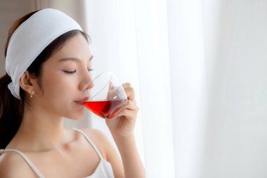 Saç bandı takmış, çay içen güzel, genç Asyalı bir kadın. Oturma odasından memnun, çay ya da içecek bir kadın. Sağlık ve rahatlama, yaşam tarzı ve sağlık için..