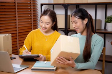 Çevrimiçi iş planlarken çalışan iki genç Asyalı kadın ve evde tablet ile sipariş kontrolü, çevrimiçi satıcı ile perakende satış, girişim işi ve kargo, nakliye ve hizmet.