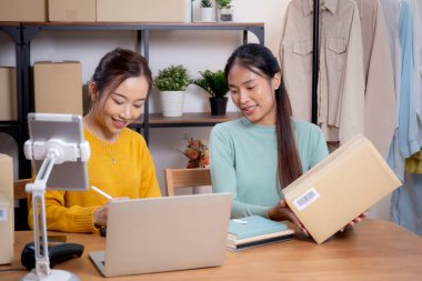Çevrimiçi iş planlarken çalışan iki genç Asyalı kadın ve evde tablet ile sipariş kontrolü, çevrimiçi satıcı ile perakende satış, girişim işi ve kargo, nakliye ve hizmet.