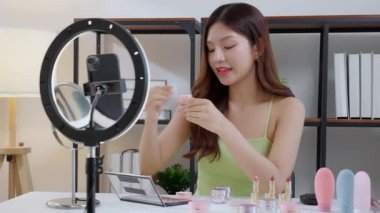 Güzel, genç Asyalı bir kadın evde aynaya bakarken kırışıklıklar için yüzüne krem sürüyor, güzel bir kadın yanağına losyon nemlendirici sürüyor, cilt bakımı ve güzellik, rahat bir şekilde kendine bakım yapıyor..