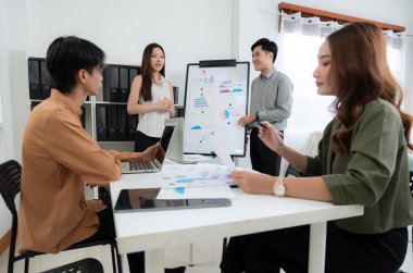 Grup Asyalı iş adamları raporlama ve sunum grafikleri ve grafikleriyle finansman hakkında ofiste toplanırken, meslektaşlar rapor ve stratejiyi, takım çalışması planlama ve analizi tartışacaklar..