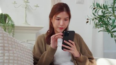 Genç Asyalı kadın akıllı telefonu evdeki Al Chatbot 'la sohbet etmek için kullanıyor. İletişim ve teknoloji. Akıllı telefondaki kadın sohbet robotu..