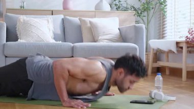 Genç Asyalı adam evde oturma odasında kararlılıkla şınav çekiyor yoga minderi eğitimi alıyor vücut geliştirme gücü ve sağlıklı yaşam tarzı için uygunluk, egzersiz rutini, kişisel bakım..