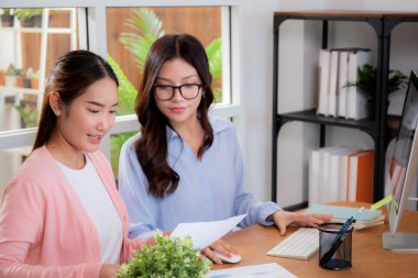 İki Asyalı iş kadını veri analizi pazarlama finansmanı ile ilgili işbirliği yapıyor, grafiklerle birlikte bilgisayar, takım çalışması ve pazarlama stratejisi planlaması üzerinde çalışıyorlar..