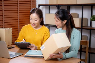 Çevrimiçi iş planlarken çalışan iki genç Asyalı kadın ve evde tablet ile sipariş kontrolü, çevrimiçi satıcı ile perakende satış, girişim işi ve kargo, nakliye ve hizmet.