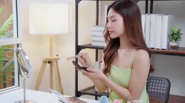 Yanağına bir ayna, güzellik ve kozmetik ile makyaj yapan mutlu, genç Asyalı bir kadın güzel, rahat bir yaşam tarzı, tatmin olmuş ve kozmetolojisi olan bir kadın..