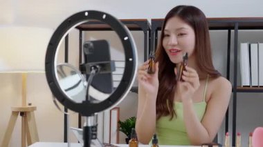 Genç Asyalı bir kadın sosyal medyaya damlalık serumu uyguluyor, içerik yaratıcısı, özbakım ve kozmetik ürünleri gözden geçirme, cilt bakımı ve kozmetik ürünleri, etki yaratan ürünleri gözden geçiriyor..