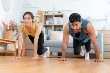 Mutlu genç Asyalı çiftler evlerinde birlikte dağcı egzersizleri yapıyor, gülümsüyor ve enerjik fitness eğitimi ve kardiyo rutini, sağlık ve refah motivasyonu..