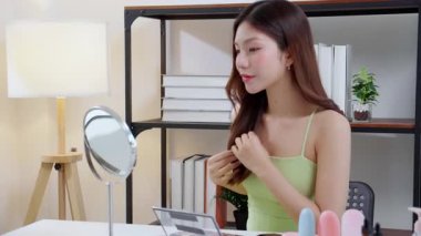 Evdeki oturma odasında kırışıklıkları kontrol etmek için aynaya bakan genç Asyalı güzel bir kadın, nemlendirici süren mutlu bir kadın. Hijyen, cilt bakımı, cilt bakımı, cilt bakımı ve cilt bakımı..