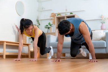 Mutlu genç Asyalı çiftler evlerinde birlikte dağcı egzersizleri yapıyor, gülümsüyor ve enerjik fitness eğitimi ve kardiyo rutini, sağlık ve refah motivasyonu..