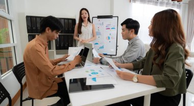 Grup Asyalı iş adamları raporlama ve sunum grafikleri ve grafikleriyle finansman hakkında ofiste toplanırken, meslektaşlar rapor ve stratejiyi, takım çalışması planlama ve analizi tartışacaklar..