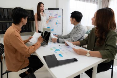 Grup Asyalı iş adamları raporlama ve sunum grafikleri ve grafikleriyle finansman hakkında ofiste toplanırken, meslektaşlar rapor ve stratejiyi, takım çalışması planlama ve analizi tartışacaklar..