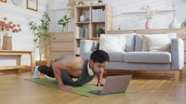 Genç adam evde Al 'ın sanal koçunu takip ederken şınav çekiyor. Güçlü olmak için akıllı fitness teknolojisi eğitimi alıyor. Dizüstü bilgisayarda yapay zeka uygulaması kullanıyor..