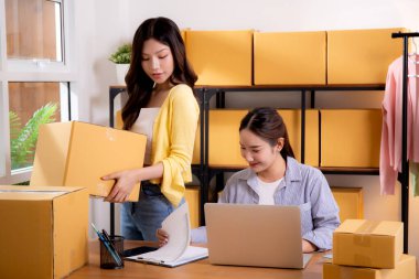 İki genç Asyalı iş kadını dizüstü bilgisayar ve belge, sevkiyat ve kargo, perakende satış ve mağaza, başlangıç veya küçük işletme, nakliye ve envanter siparişlerini kontrol ediyor.