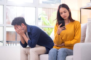 Evdeki oturma odasında ilişki sorunları yaşayan mutsuz Asyalı çift, hayal kırıklığına uğramış ve hayal kırıklığına uğramış, görmezden gelen ve ifade güçlüğü çeken çift..