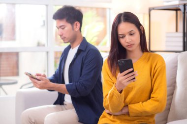 Evdeki oturma odasında ilişki sorunları yaşayan mutsuz Asyalı çift, hayal kırıklığına uğramış ve hayal kırıklığına uğramış, görmezden gelen ve ifade güçlüğü çeken çift..