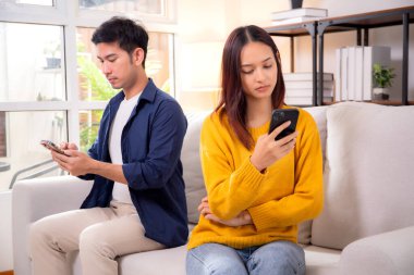 Evdeki oturma odasında ilişki sorunları yaşayan mutsuz Asyalı çift, hayal kırıklığına uğramış ve hayal kırıklığına uğramış, görmezden gelen ve ifade güçlüğü çeken çift..