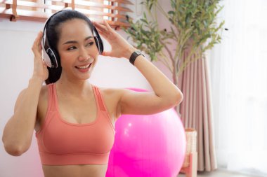 Antrenmandan sonra kulaklıkla müzik dinleyen genç Asyalı kadın yoga ve antrenmandan sonra evde dinleniyor, kadınlar eğlence, spor ve refah ile egzersiz üstüne müzik dinliyor..
