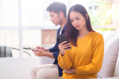 Evdeki oturma odasında ilişki sorunları yaşayan mutsuz Asyalı çift, hayal kırıklığına uğramış ve hayal kırıklığına uğramış, görmezden gelen ve ifade güçlüğü çeken çift..