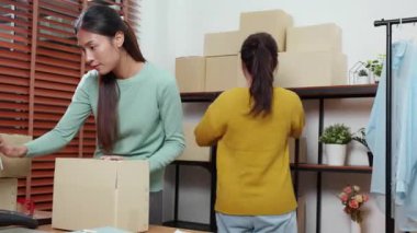 İki genç Asyalı kadın çevrimiçi kıyafet siparişleri paketliyor, karton kutuları nakliyat için hazırlıyor, küçük işletme girişimi, ekom ve girişimci, ekspres teslimat.
