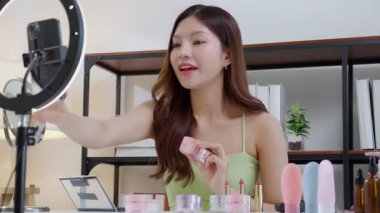 Genç Asyalı kadın kozmetik ürünlerini sosyal medya platformunda takipçiler, krem ya da losyonu canlı yayında inceleyen, etkileyen ve gözden geçiren kadınlar için heyecan verici bir şekilde sunup gözden geçiriyor..