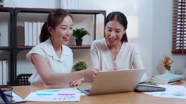 İki Asyalı iş kadını dizüstü bilgisayar kullanırken satış ve pazarlama başarısından sonra beşlik çakıyor. Mutlu iş adamları birlikte kutlama yapıyor. Dizüstü bilgisayar ve başarı arayan bir kadın..