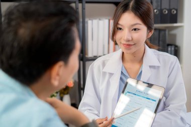 Asyalı beslenme uzmanı, AI ile kişiselleştirilmiş yemek planını sağlık hizmetleri danışmanlığı sırasında hastaya açıklamak için tablet kullanıyor, sağlıklı yaşam tarzı, kadın diyetçisi, tablette yapay zekayla beslenme planı gösteriyor..