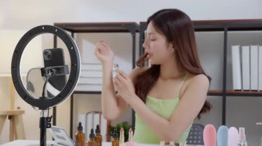 Genç Asyalı güzellik etkileyicisi, evde makyaj incelemesi yaparken kolunda birden fazla ruj gölgesi test ederken, içerik yaratıcısının sosyal medyada kozmetik ürünü ve sunumu, güzellik ve bakım.