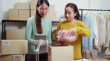 İki genç Asyalı kadın çevrimiçi kıyafet siparişleri paketliyor, karton kutuları nakliyat için hazırlıyor, küçük işletme girişimi, ekom ve girişimci, ekspres teslimat.