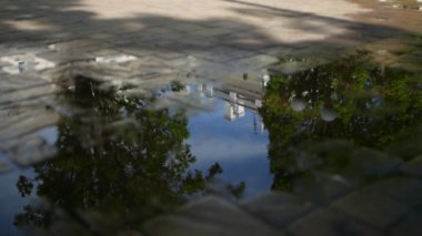 Bahar ya da yaz stok görüntüleri. Şehir binalarının ve gökyüzünün yakın yansıması yağmurdan sonra kaldırım taşının kaldırımındaki su birikintisindeki bulutlar..