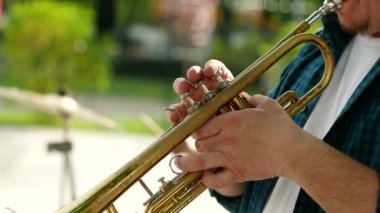 Parkta müzik aleti çalan bir trompetçinin elleri. Açık hava konseri sırasında sokak performansı. Bando sahneye çıkıyor..