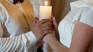 Düğün töreninde yeni evlilerin ellerinin mum tutarken yakın plan çekimleri. Birbirine aşık bir çiftin güzel video görüntüleri..