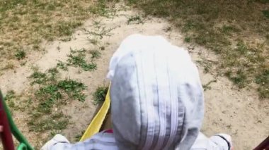 little happy girl slides down on a slide, laughs and smiles. Happy child plays on playground outdoors.