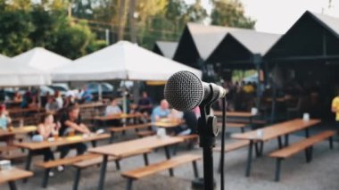 Close up stand with microphone and audience in the background. Preparing for an outdoor concert.