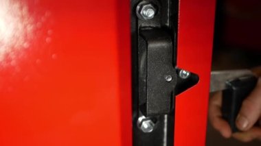 Production of biofuel boilers. A man opens the door of a new red solid fuel boiler.