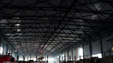 İnşaat kaynakçısı yükseklikte çalışır. Modern depo inşaatı, yapısal çelik yapı yeni ticari bina. Kaynakçı inşaat alanında çalışıyor. Metal parçalarının kaynak süreci